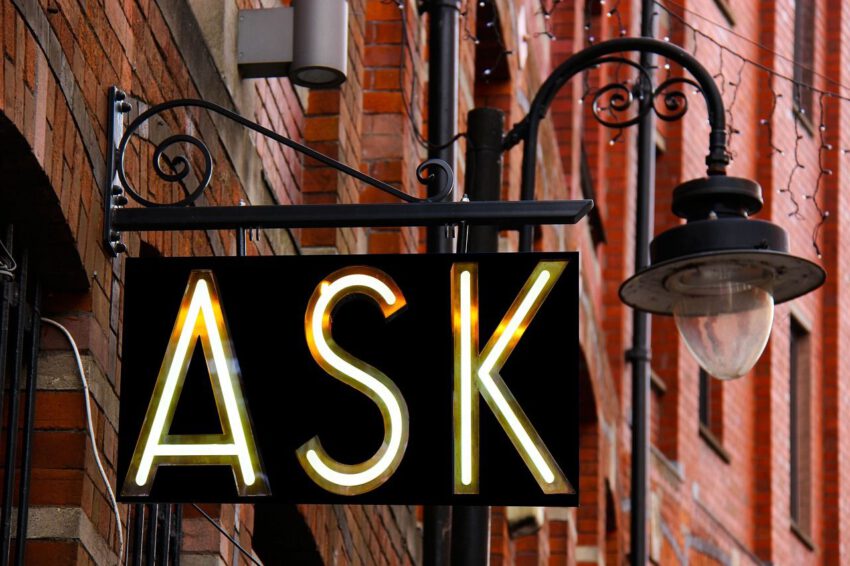 An der Rotklinkerfassade eines Stadthauses, vor einer Strassenlampe im Retrostil, hängt ein Metallschild mit den Großbuchstaben "ASK".
